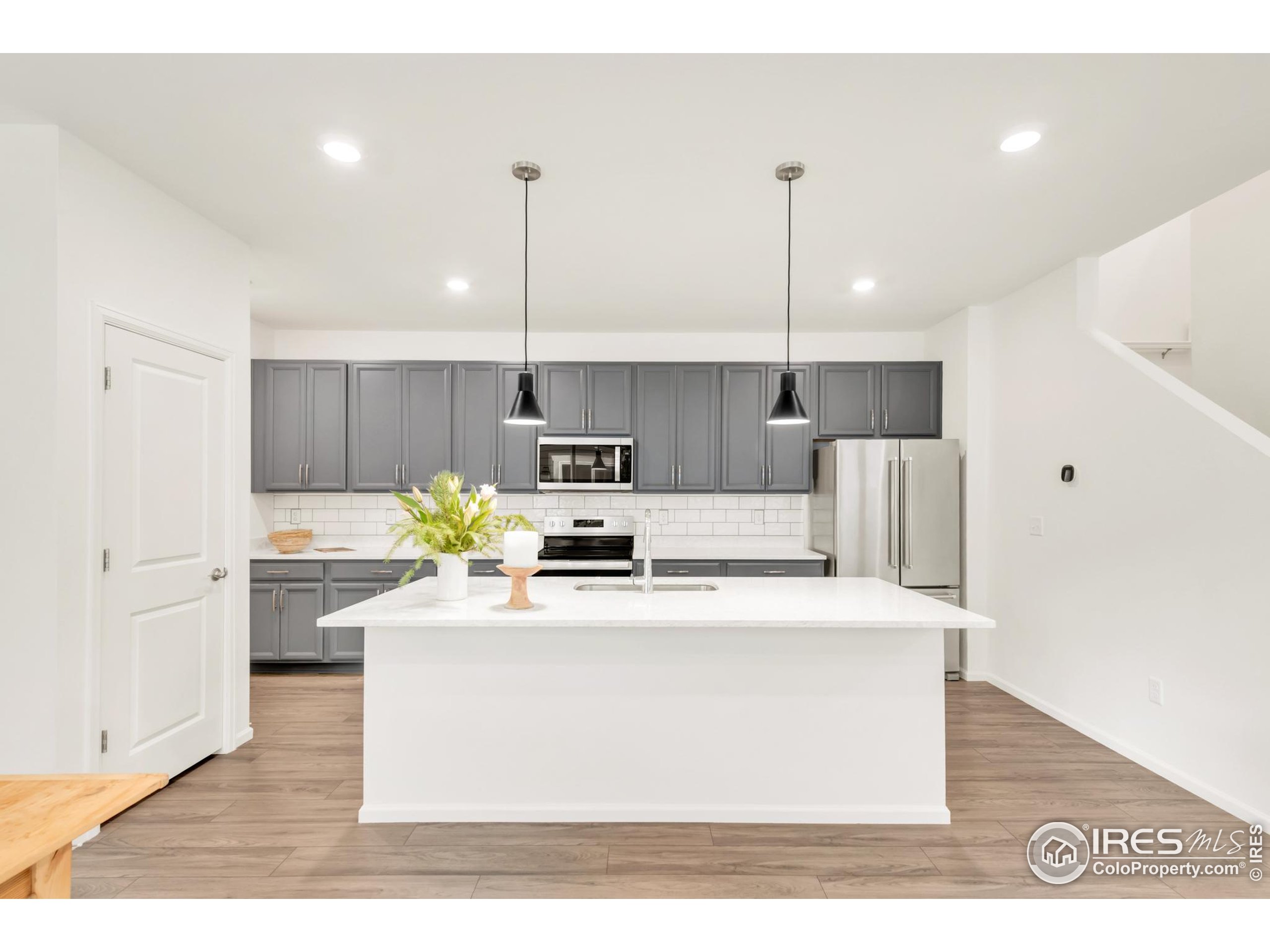 2455 Alpine Street Longmont, CO 80504 - Photo 10 of 30 a view of a kitchen with kitchen island stainless steel appliances a sink a counter top space cabinets and wooden floor