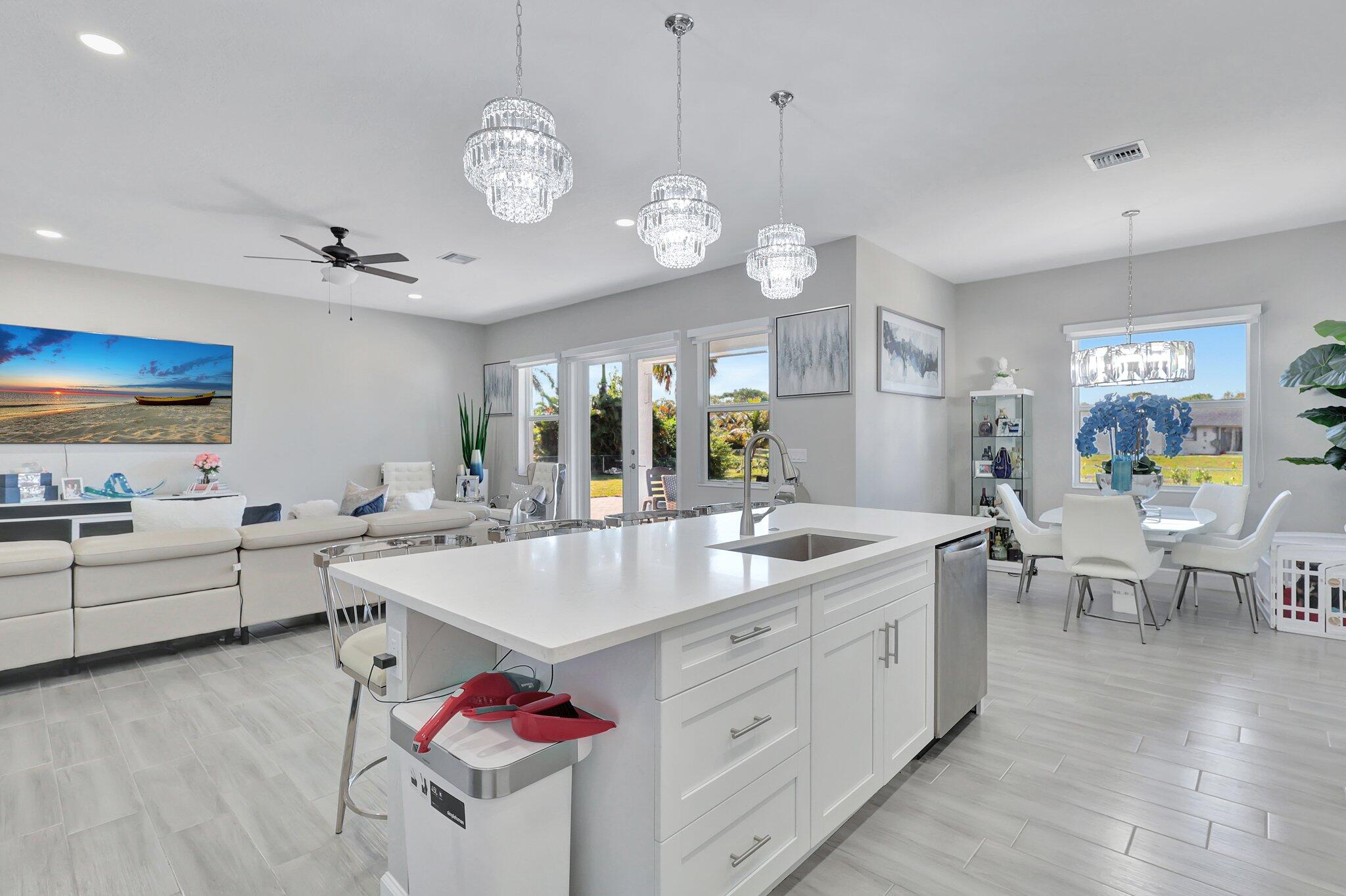 a large white kitchen with lots of counter space and chandelier
