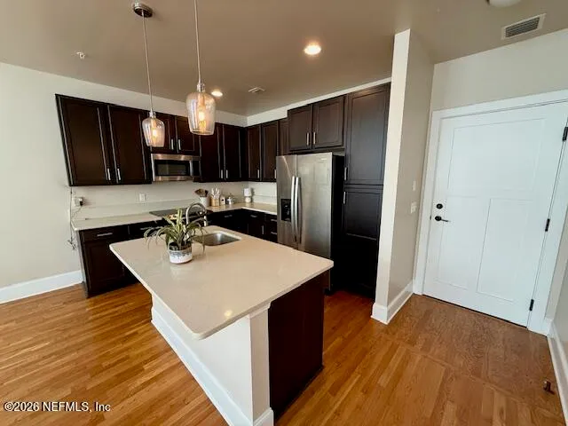 a large kitchen with stainless steel appliances a large counter top a stove a refrigerator and a cabinets