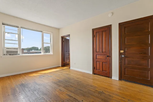 an empty room with wooden floor closet and windows