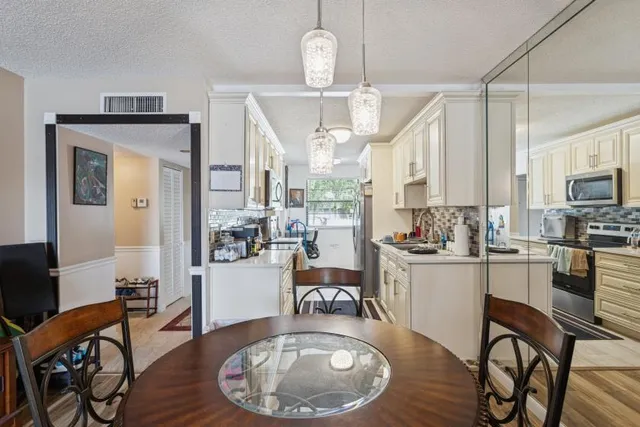 a kitchen with stainless steel appliances granite countertop a stove a refrigerator a kitchen island a dining table and chairs with wooden floor