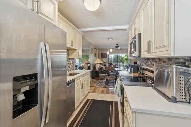 a kitchen with stainless steel appliances a refrigerator a sink a stove and white cabinets