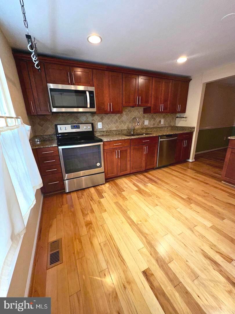 5718 Wood Mouse Court Burke, VA 22015 - Photo 3 of 23 a kitchen with stainless steel appliances wooden cabinets a sink and a stove