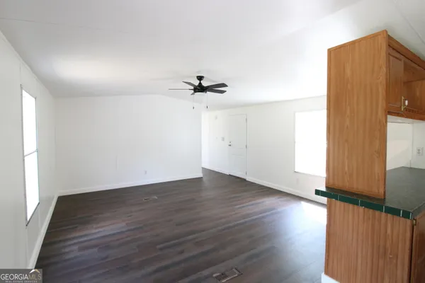 an empty room with wooden floor fan and windows