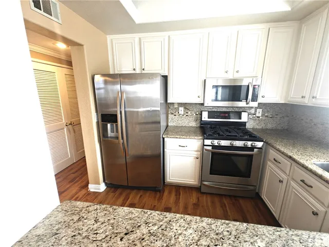 a kitchen with stainless steel appliances granite countertop a refrigerator a stove a sink and a window