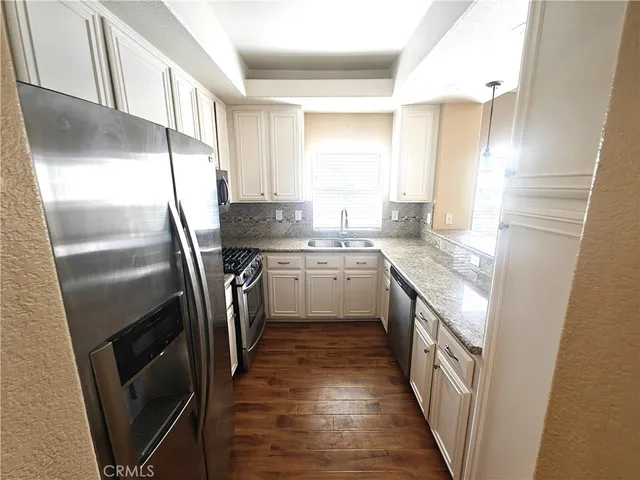 a kitchen with stainless steel appliances granite countertop a sink a stove a refrigerator and cabinets