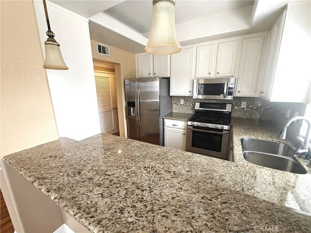 a kitchen with stainless steel appliances granite countertop a sink refrigerator and microwave