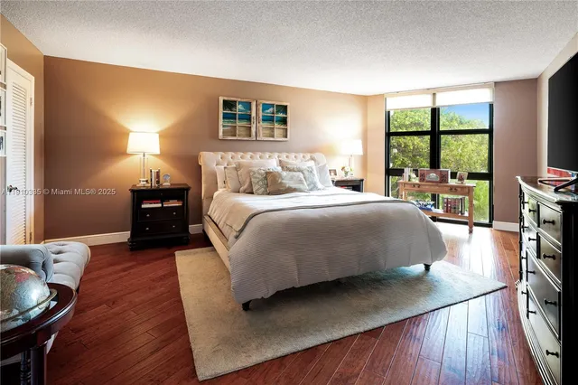 a bedroom with a bed a large window and wooden floor