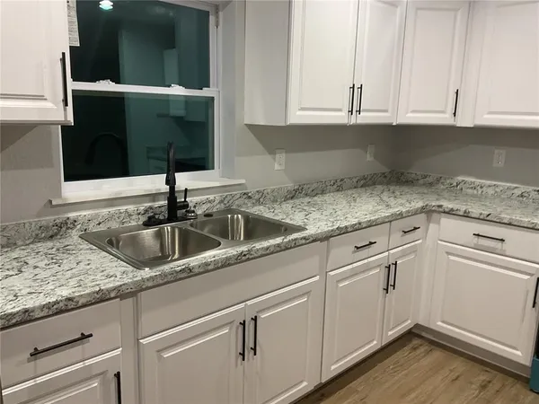 a kitchen with granite countertop a sink and a stove top oven