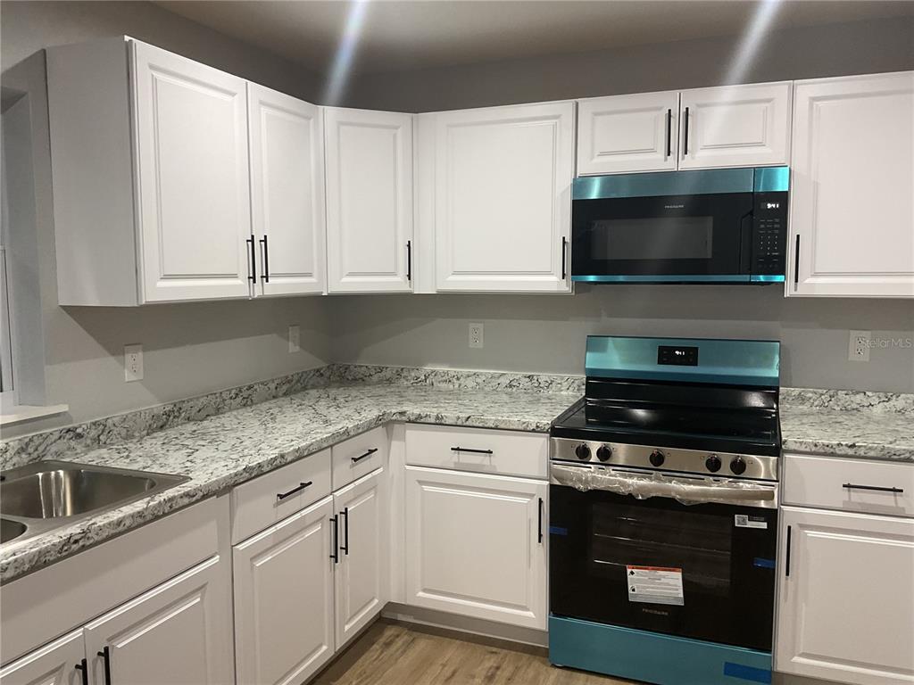 2432 Northwest 5th Street Okeechobee, FL 34972 - Photo 15 of 24 a kitchen with granite countertop a sink and a stove top oven