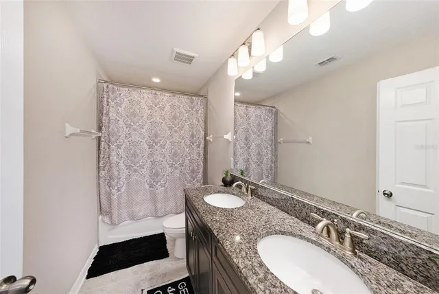 a bathroom with a granite countertop sink a mirror and a shower