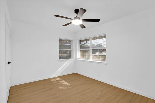 a view of empty room with wooden floor and fan