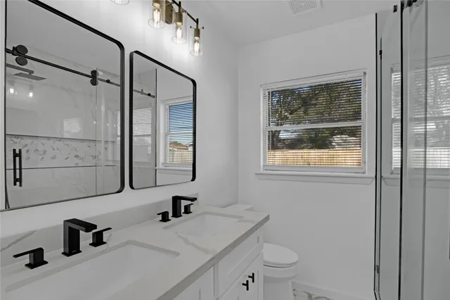 a bathroom with a sink a toilet and shower