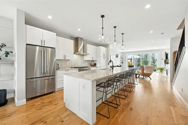 a large kitchen with stainless steel appliances a refrigerator a stove a sink dishwasher and a dining table with wooden floor