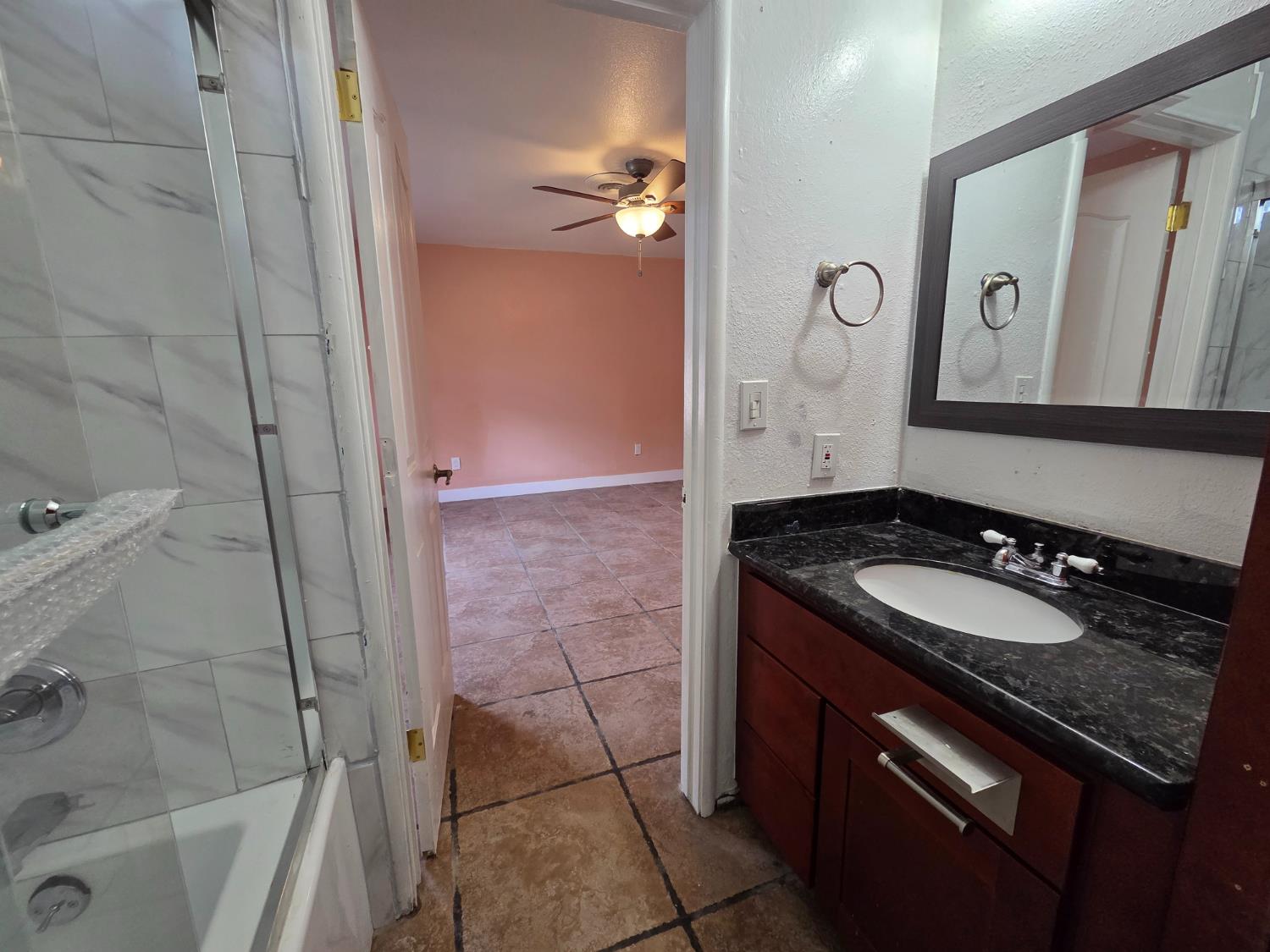5010 Powerline Road, Unit D Olivehurst, CA 95961 - Photo 8 of 12 a bathroom with a granite countertop sink a mirror and a shower