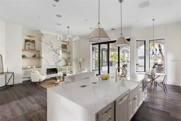 a kitchen with stainless steel appliances granite countertop a stove a kitchen island a chandelier and living room view