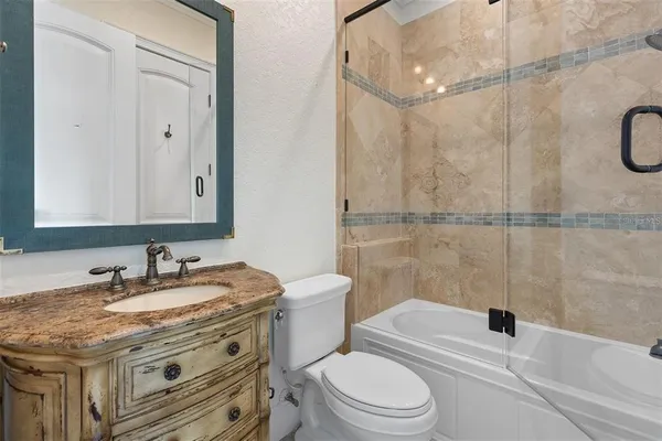 a bathroom with a granite countertop sink toilet a mirror and shower