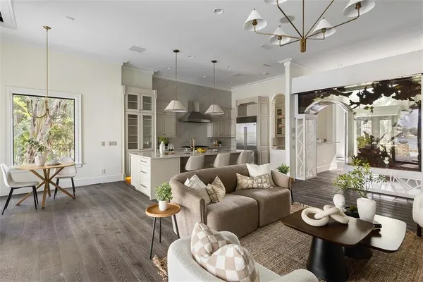 a living room with furniture kitchen view and a wooden floor