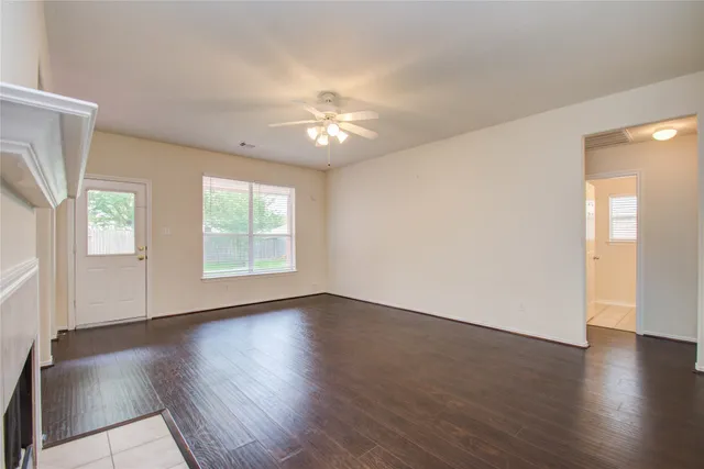 an empty room with wooden floor fireplace and windows