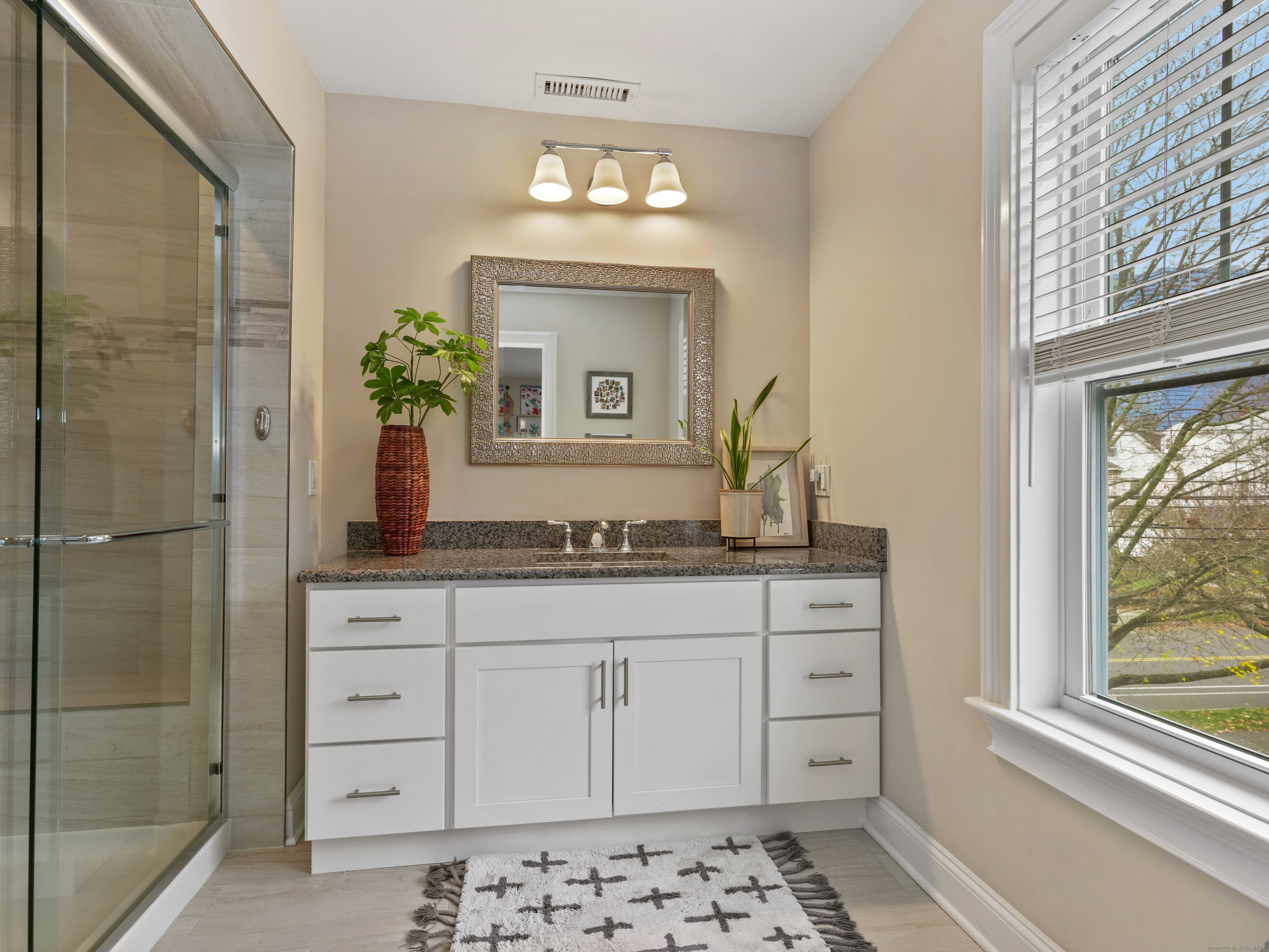 91 West Broad Street, Unit 11 Stamford, CT 06902 - Photo 19 of 26 a bathroom with a granite countertop sink a mirror and a shower