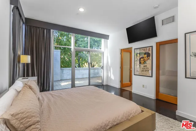 a bedroom with a large bed and a flat tv screen