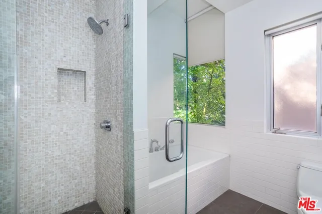 a bathroom with a white bath tub a window and a shower