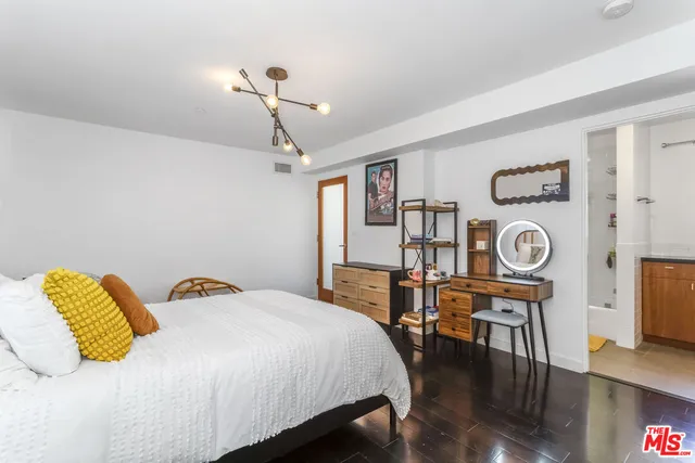 a bedroom with a bed a dresser with wooden floor