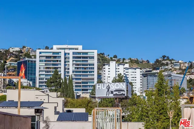 a view of a house with potted plants and a bench