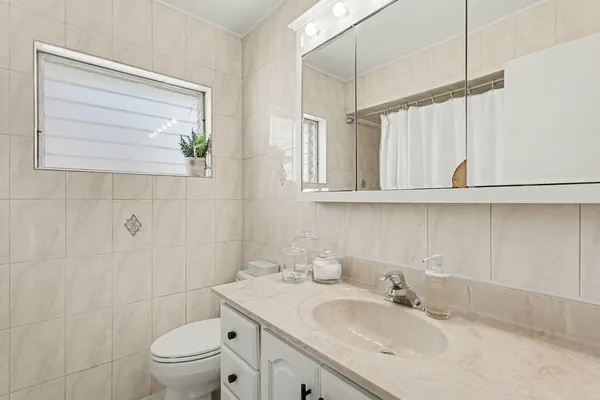 a bathroom with a granite countertop sink a toilet and a mirror