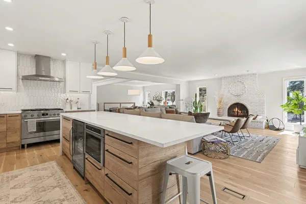 a large kitchen with stainless steel appliances granite countertop a stove a sink a oven and a dining table with wooden floor