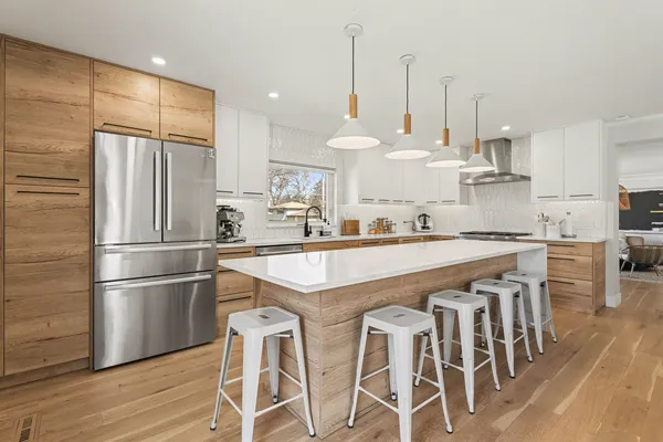 a kitchen with stainless steel appliances granite countertop a refrigerator a sink dishwasher a stove and white cabinets with wooden floor