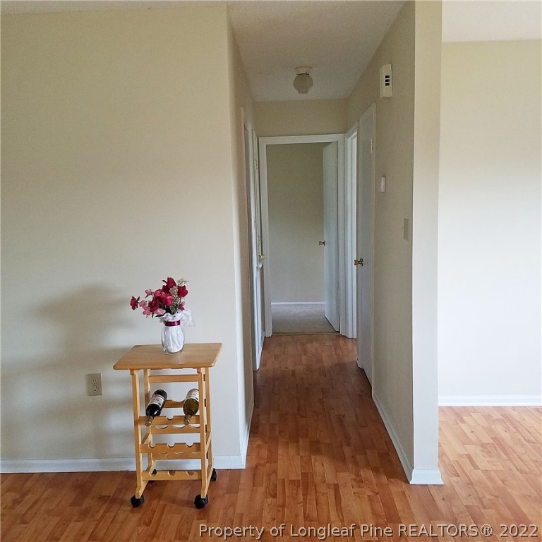 6596 Fisher Road Fayetteville, NC 28304 - Photo 9 of 27 a view of a hallway to a livingroom with wooden floor and furniture