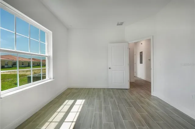 a view of empty room with wooden floor and fan