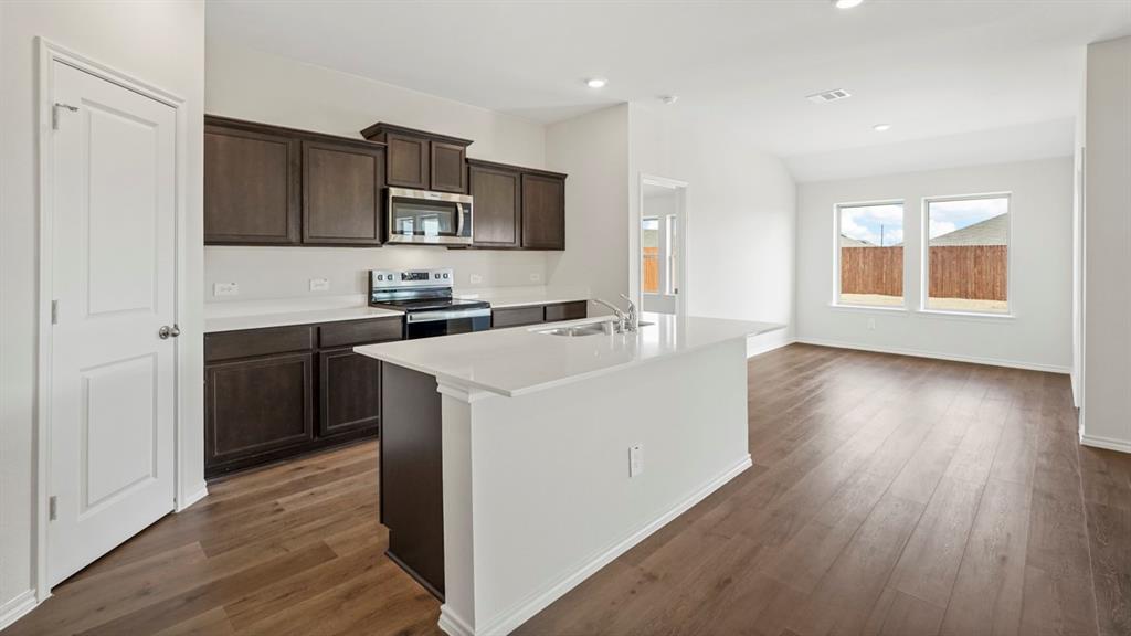 512 Yellow Rose Road Princeton, TX 75407 - Photo 26 of 37 a kitchen with stainless steel appliances a sink cabinets and wooden floor