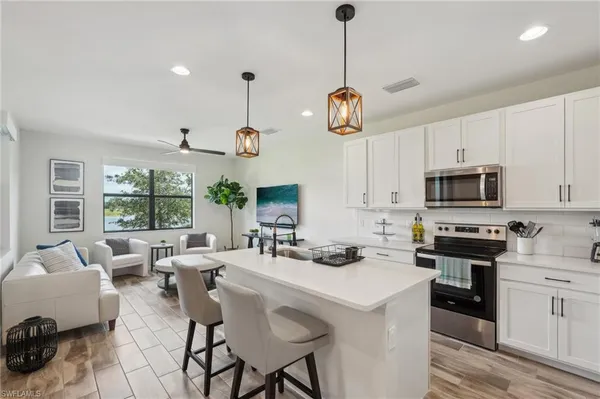 a kitchen with stainless steel appliances a stove a sink a center island and windows