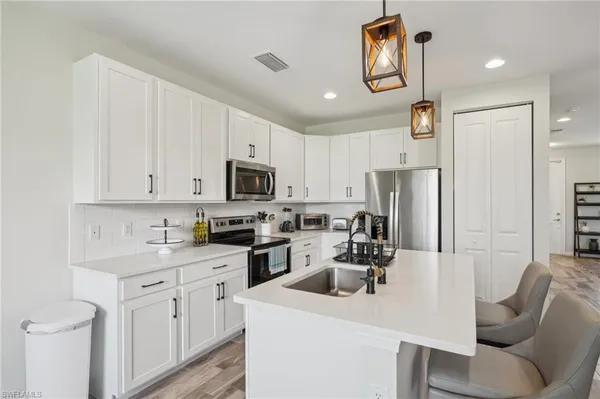 a kitchen with stainless steel appliances white cabinets a sink a stove a refrigerator and white cabinets