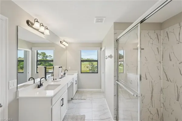 a bathroom with a double vanity sink mirror and shower