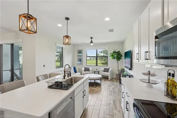 a kitchen with stainless steel appliances a stove a sink a center island and windows
