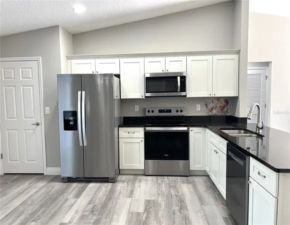 a kitchen with stainless steel appliances granite countertop a refrigerator stove a sink and a microwave