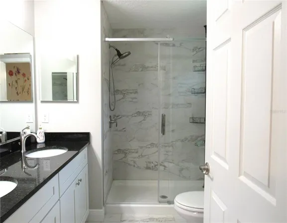 a bathroom with a granite countertop sink toilet and shower