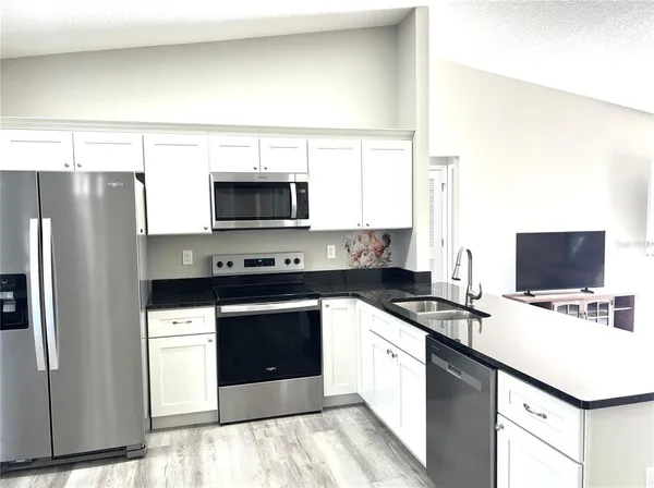 a kitchen with stainless steel appliances a stove a sink a microwave a refrigerator a cabinets and a counter top space