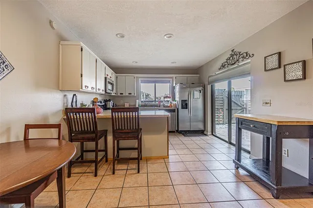 a living room with stainless steel appliances furniture a rug and a kitchen view