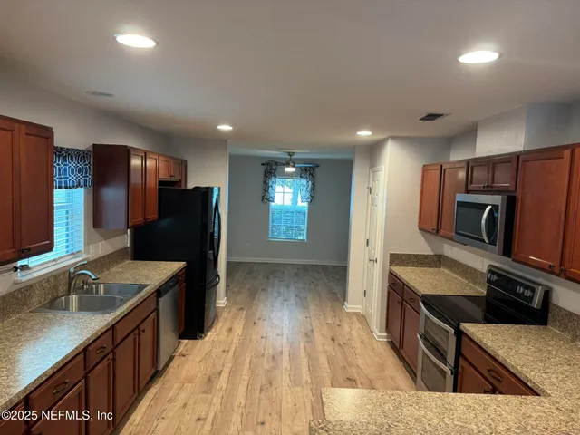 a large kitchen with stainless steel appliances granite countertop a sink stove and refrigerator