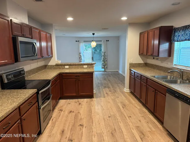 an empty room with wooden floor chandelier and windows
