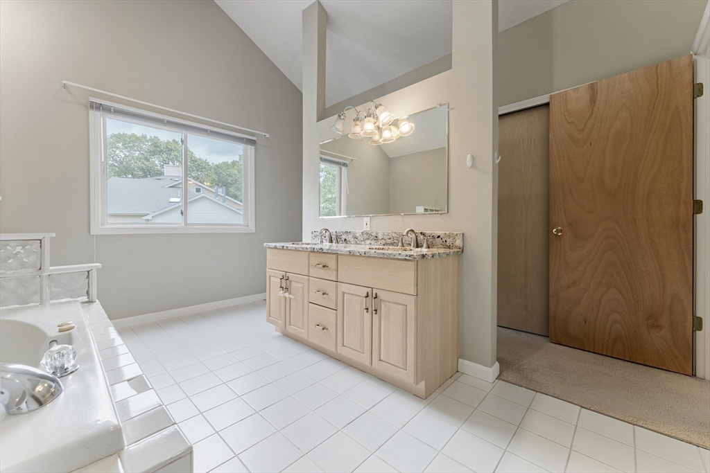 22 Arrowhead Circle, Unit 22 Ashland, MA 01721 - Photo 22 of 35 a bathroom with a granite countertop sink a mirror a vanity and a bathtub