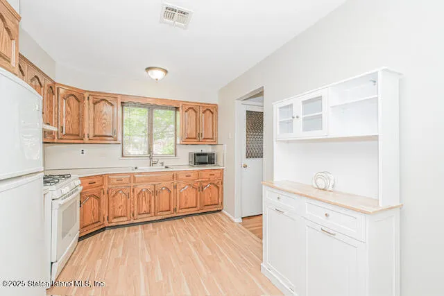 a large white kitchen with granite countertop a lot of counter space and wooden floor