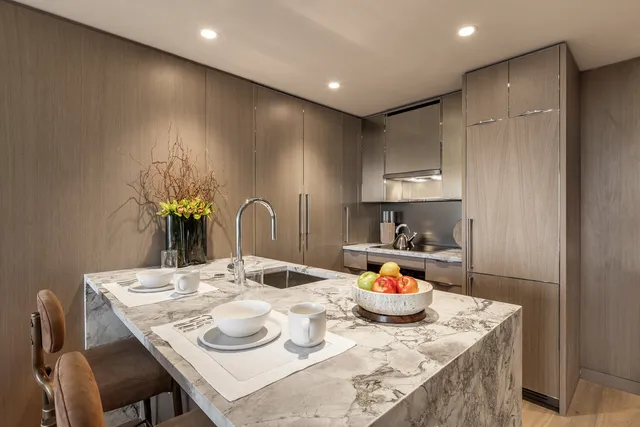 a kitchen with kitchen island stainless steel appliances a table chairs sink and cabinets