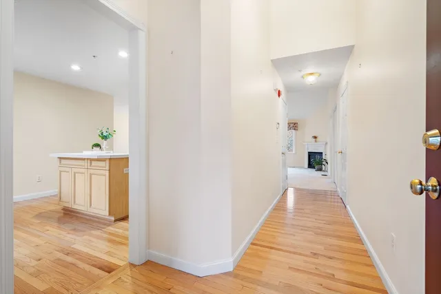 a view of a hallway with wooden floor and a bathroom