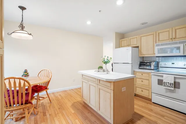 a kitchen with stainless steel appliances granite countertop a dining table chairs refrigerator and sink