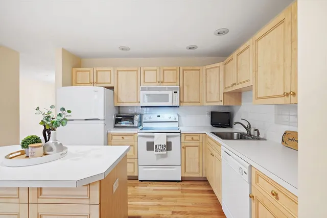 a kitchen with stainless steel appliances a sink a stove a refrigerator a center island cabinets and a window